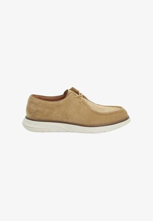 Chaussure décontractée beige en daim avec lacets, semelle en caoutchouc blanc et couture moc toe, vue de profil latéral sur fond blanc.