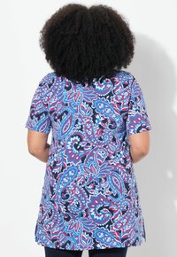 Tunique à manches courtes en marine avec un motif paisley éclatant aux couleurs rouge, bleue et blanche. Coupe décontractée avec fentes sur les côtés pour plus de confort.