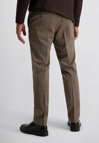 Bruine, textuurgeweven pantalon met een slim fit, voorzien van een enkele achterzak en lichte plooien, aangevuld met zwarte instappers.