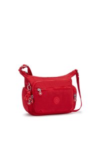 Red nylon shoulder bag with adjustable strap, featuring two zippered pockets and a keychain charm, smooth texture, and logo accent.