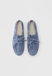 Mocassini in camoscio azzurro chiaro con chiusura a lacci, dettaglio di frange sulla tomaia e punta arrotondata. Finitura testurizzata.