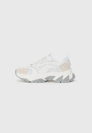Chunky white sneakers with grey accents, mesh and synthetic materials, rounded toe, textured side panels, and a thick rubber sole.