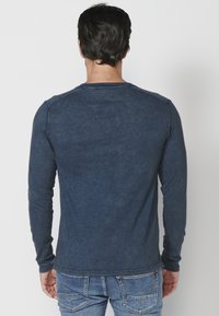 Pánská košile s dlouhým rukávem, modrošedá texturovaná látka, kulatý výstřih, slim fit, s dekorativním prošíváním na ramenních švech.