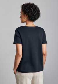 Svart kortärmad t-shirt gjord av bomull, med rund halsringning och avslappnad passform, visad bakifrån med enkel design.