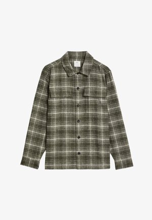 Chemise à carreaux verts en tissu doux, avec un col pointu, des manches longues, et une fermeture à boutons avec des boutons foncés et deux poches poitrine.