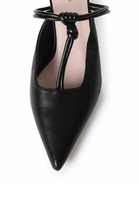 Zwarte lederen schoen met spitse neus, een geknoopte banddetail, open zijkanten en een lichtroze binnenzool. Gladde textuur overal.
