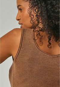 Brown ribbed tank top with a fitted design. The fabric features a textured pattern, showcasing wide shoulder straps and a scoop neckline.