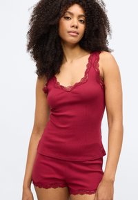 Μπορντό ριμπ αμάνικη μπλούζα με δαντέλα στο τελείωμα και αντίστοιχα σορτς. Το ύφασμα είναι απαλό, με άνετη εφαρμογή και λεπτές δαντελένιες λεπτομέρειες στις άκρες.