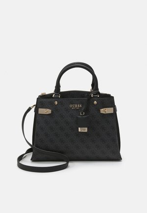 Czarna torebka Guess z monogramem, złotymi elementami, górnymi rączkami, odpinanym długim paskiem oraz przednią plakietką z logo na białym tle.
