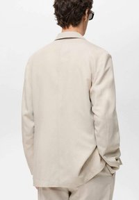 Beige blazer made of a lightweight fabric; plain design with a single vent at the back and a notched collar; tailored fit.