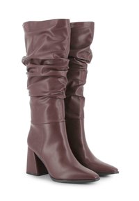 Botas de cuero marrón, holgadas, hasta la rodilla, con punteras puntiagudas y tacones altos de estilo robusto.