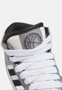 Sneaker da basket alta in materiale sintetico grigio con lacci bianchi, con un logo a forma di pallone da basket sulla linguetta e accenti neri in contrasto.