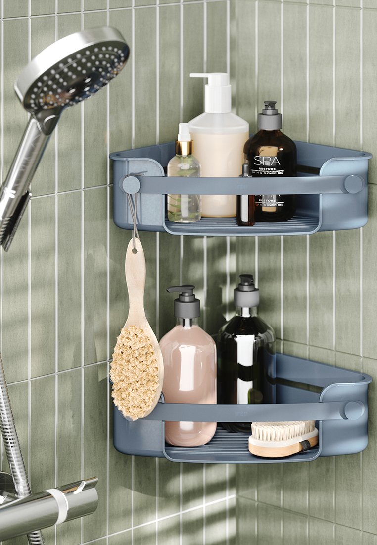 Dwupoziomowy niebieski plastikowy organizer na przybory do kąpieli z zaokrąglonymi krawędziami, trzymający różne butelki oraz szczotkę z naturalnego włókna, zamocowany na ścianie wyłożonej kafelkami.