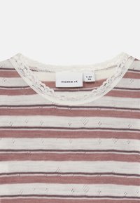 Chemise à manches courtes rayée avec une base blanche, des rayures mauves et marron foncé, un col en dentelle texturée et de petits motifs à pois sur l'ensemble.