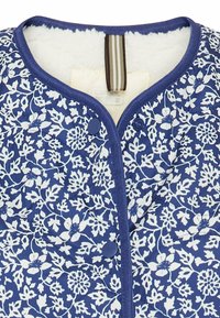 Quilted jacket in navy blue with white floral pattern, featuring a round collar, snap buttons, and a soft, textured interior lining.