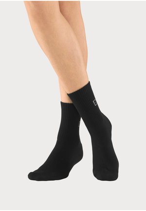 Schwarze Knöchelsocken aus geripptem Stoff, mit einem Logodetail an der Seite und einem engen Sitz am Bündchen.