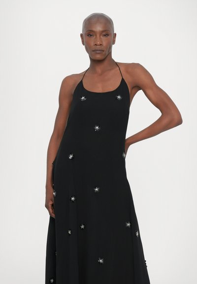 Black sleeveless dress with a fitted bodice, flowing skirt, and decorative silver flower embellishments evenly spaced throughout.