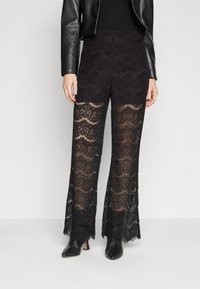 Zwarte kanten broek met een gegolfd patroon en wijde pijpen, met een semi-doorzichtige textuur en een aansluitende tailleband.