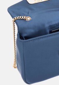 Borsa a tracolla in raso blu navy con catena dorata e hardware decorativo. Presenta una forma strutturata e un'unica compartimento aperto all'interno.