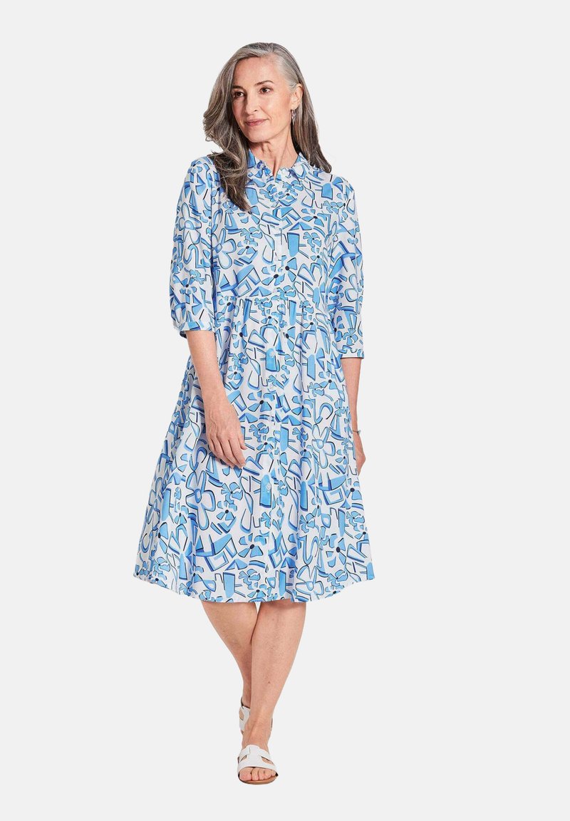 Blau-weißes Kleid mit Muster, Kragen, Dreiviertelärmeln und schwingendem Rock. Der Stoff wirkt leicht und hat eine glatte Textur.
