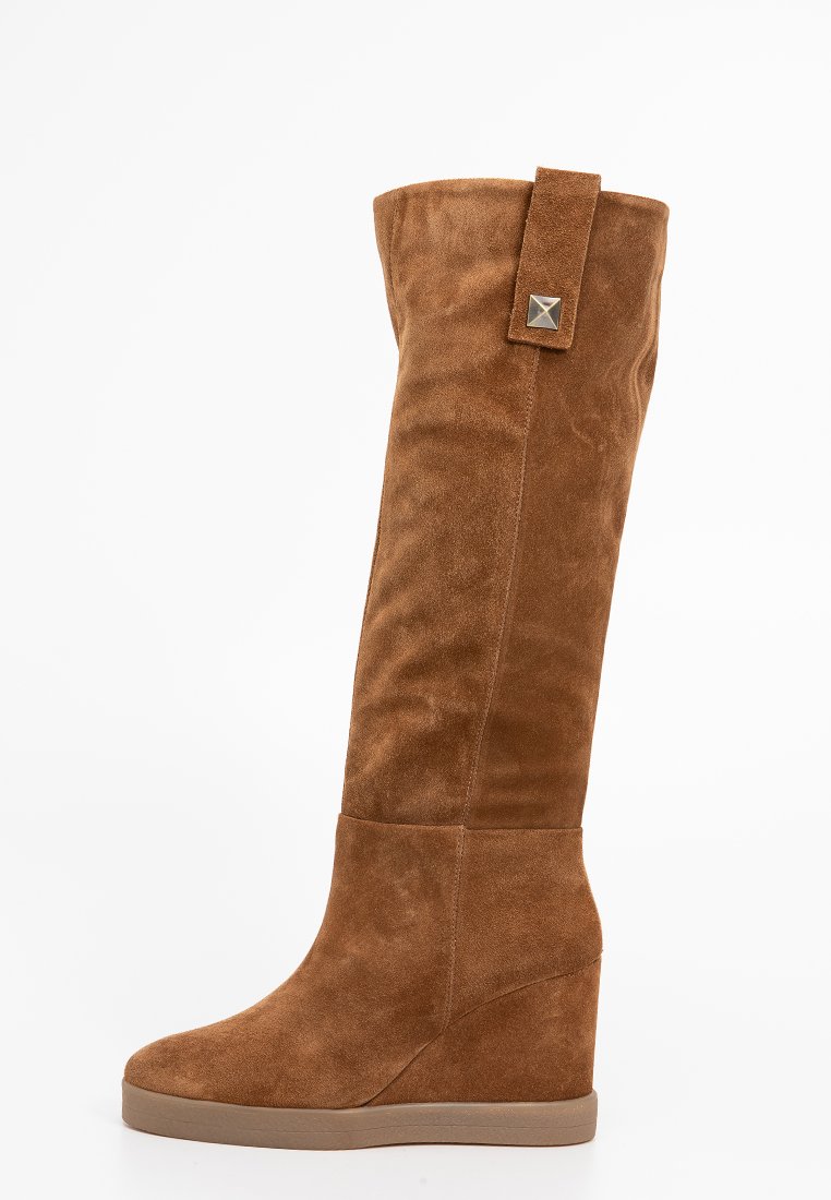 Bottes à talons en suede marron, avec une texture lisse, présentant un large revers et un accent métallique sur la sangle, conçues pour un ajustement sécurisé.