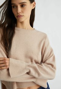 Maglione a maglia di colore rosa chiaro con polsini e orlo a coste. Vestibilità comoda, maniche ampie e texture morbida. Scollo rotondo semplice e design casual.