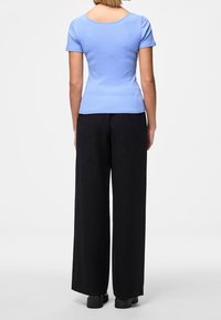 Světle modrý úzký top s krátkým rukávem, doplněný černými širokými kalhotami. Hladká textilie, kulatý výstřih a přiléhavý střih.