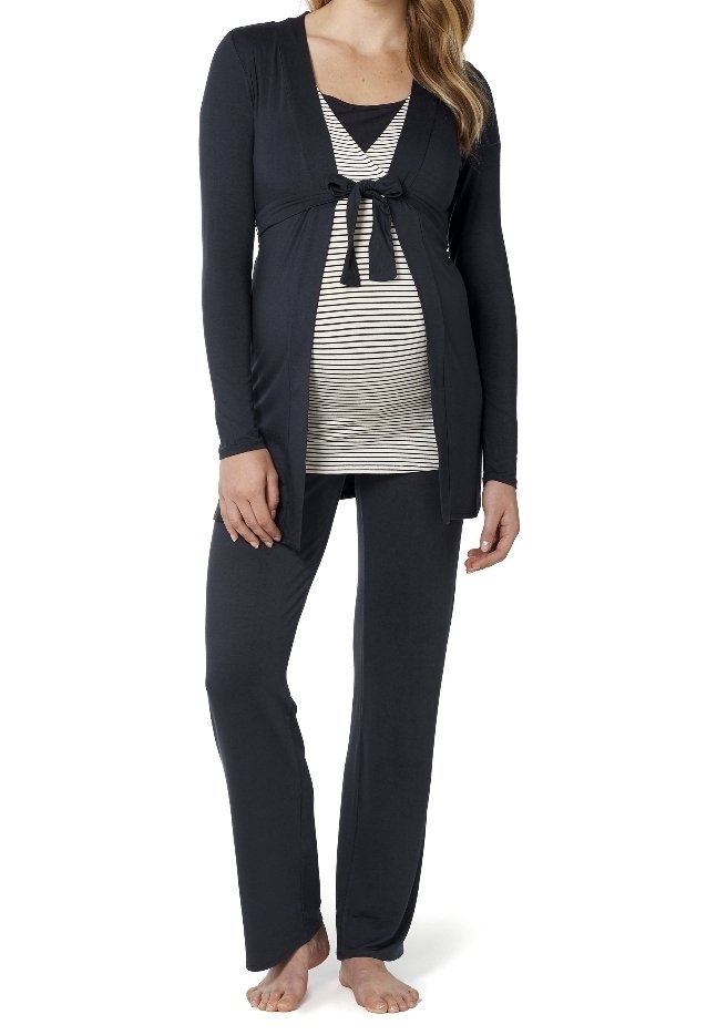 Femme enceinte portant un cardigan noir ouvert noué au-dessus d'un haut de maternité rayé et d'un pantalon de maternité noir, pieds nus sur fond blanc.