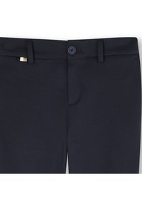 Calças azul-marinho com fecho de botão, frente lisa e tecido texturizado subtil. Incluem uma pequena etiqueta da marca multicolorida na cintura.