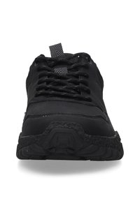 Schwarze Sportschuhe mit einer strukturierten Gummisohle, schwarzen Schnürsenkeln und einer gemusterten Zunge, entwickelt für Komfort und Leistung.