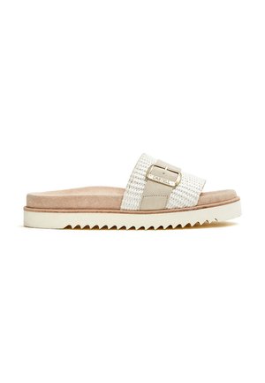Sandalia tipo slide con parte superior trenzada en crema y beige claro, con un hebilla metálica. Plantilla texturizada sobre una suela blanca con cortes en zigzag.