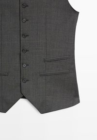Szary materiałowy kamizelka z teksturowanym splotem, sześcioma czarnymi guzikami oraz dwiema kieszeniami bocznymi z wykończonymi krawędziami. Dopasowany krój z dłuższym tyłem.