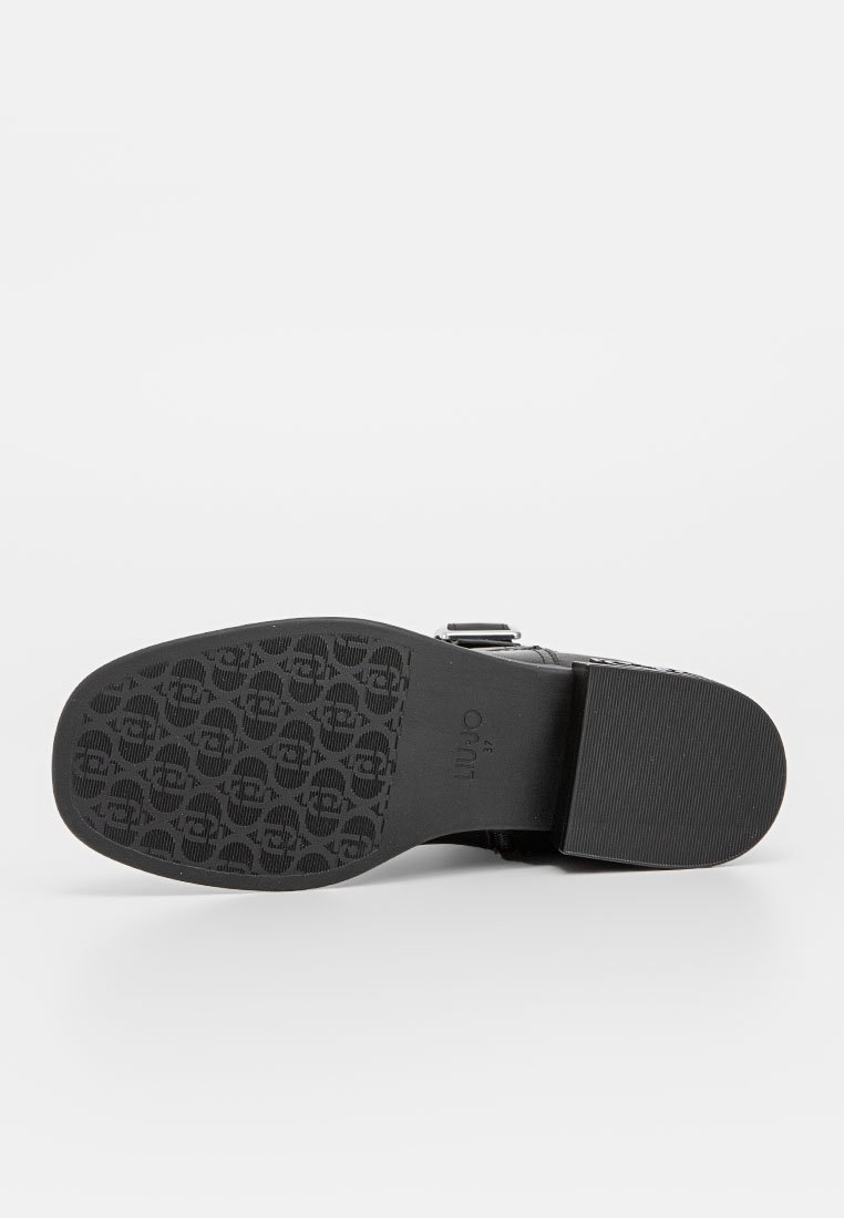 Suola di scarpa nera con motivo testurizzato, caratterizzata da una serie di design circolari in rilievo. Il materiale sembra essere gommato con una finitura liscia.