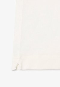 Vit bomullströja med en texturerad yta, som har en liten sidoklyvning i nederkant för extra detalj. Klassisk rund halsringning.