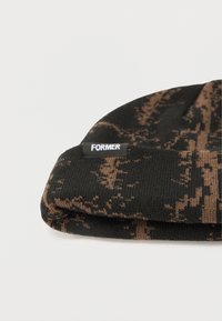 Μαύρος και καφέ πλεκτός σκούφος με διπλωμένη ρεβέρ και μικρή ορθογώνια ετικέτα με την ένδειξη "FORMER." Μαλακή υφή με εφαρμοστή εφαρμογή.