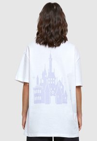 Bijela pamučna majica s velikim grafikom lavandastog dvorca na leđima. Kratki rukavi i ležeran kroj. Glatka tekstura.