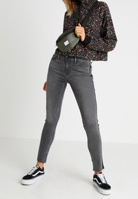 Jeans skinny grigi a vita alta, cuciture a contrasto e felpa nera floreale corta. Abbinate a sneakers nere e bianche.