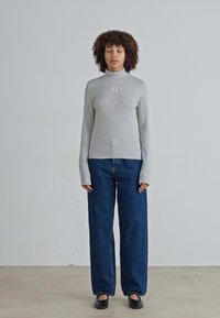 Gray long-sleeve turtleneck top with a ribbed texture, paired with high-waisted blue denim jeans. Black slip-on shoes complete the outfit.