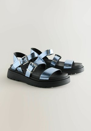 Kék fémes, pántos szandálok állítható csatakkal, fekete vastag talppal, nyitott orrdesignnal, sima felülettel és modern stílussal.