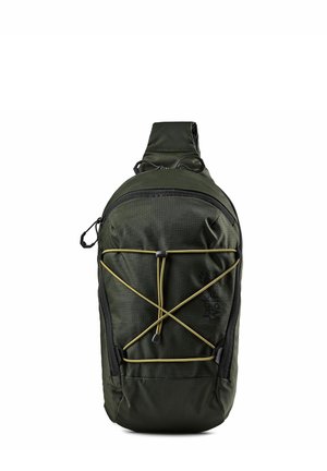 Donkergroene éénriemige slingrugzak met elastisch koord aan de voorkant, ritssluitingen en "Jack Wolfskin" logo aan de voorkant.