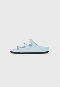 Light blue sandals with three adjustable buckles, a flat sole, and a textured, rubber bottom for grip.