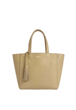 Sac fourre-tout en cuir beige avec deux poignées et un pompon décoratif suspendu à une poignée, sur fond blanc.