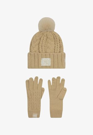 Cappello beige lavorato a maglia con un motivo a cavi testurizzato e un pon pon sulla sommità; guanti abbinati lavorati a maglia con dettagli a cavi e polsini elasticizzati.
