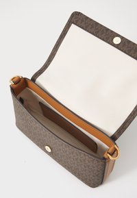 Brown patterned handbag with a magnetic closure, tan interior lining, and a single shoulder strap. Includes a slip pocket inside.