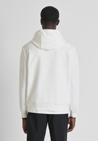 Sudadera blanca con capucha, con una textura suave y una costura en la parte trasera. Las mangas largas y los puños elásticos completan el diseño.