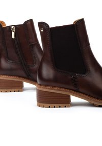 Bottes chelsea en cuir marron avec fermeture éclair sur le côté, panneau élastique, talon en bois et semelle en caoutchouc texturé. Surface lisse avec des coutures décoratives.