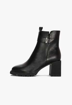 Czarne skórzane botki za kostkę na słupku, o zaokrąglonym nosku, z bocznym paskiem ze srebrną klamrą i uchwytem na tylnej części cholewki.