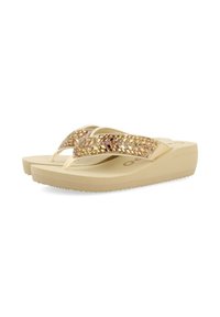 Chanclas beige con una plataforma texturizada. Las correas presentan un diseño geométrico, acentuado con adornos iridiscentes. Suela plana.