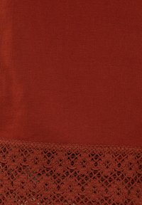 Roestkleurige stof met een gladde textuur, voorzien van een gedetailleerde kanten rand langs de onderkant met bloemmotieven.