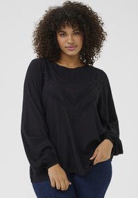 Black, long-sleeve blouse featuring a woven lace detail in a chevron pattern on the front. Soft fabric with gathered accent at cuffs.